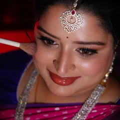 A close-up getting-ready shot. Applying blush to add a warm, rosy glow to the bride's cheeks for her engagement.