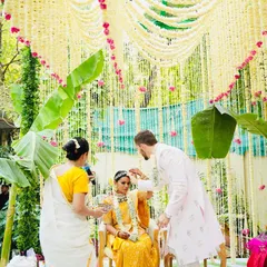 This moment captures the heart of a fusion wedding. We created a stunning backdrop of tuberose curtains and fresh banana leaves for a traditional South Indian ceremony, where the groom lovingly places the mangalsutra, embracing his partner's culture.