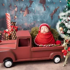 The best Christmas gift of all. This newborn is nestled safely in a festive red truck, surrounded by presents and decorations. It is a perfect setup for a holiday birth announcement.