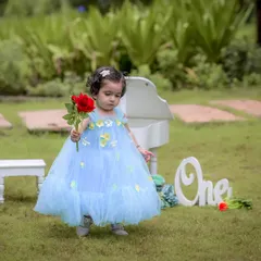 A simple red rose for a little princess on her first birthday. The soft, natural light of the park setting complements her delicate blue dress, making for a dreamy and timeless portrait.