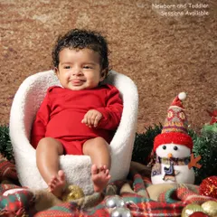 A happy baby enjoying our Christmas setup. Dressed in a bright red outfit, this little one is all smiles next to a snowman prop, perfectly capturing the joy of the season.