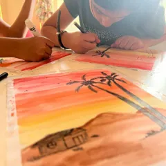 Adding the final touches. After painting the watercolor background, the kids use black markers to draw silhouettes, learning about foreground and background.