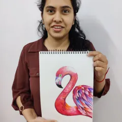 An adult student smiles as she holds her finished color pencil drawing of a flamingo, showcasing beautiful blending and vibrant color work.