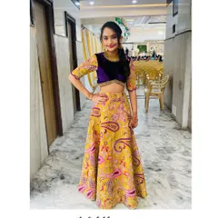 A modern lehenga set featuring a yellow paisley print skirt and a rich purple velvet crop top.