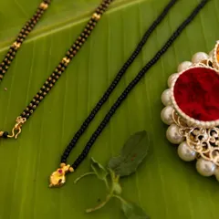 A beautiful flat lay of traditional wedding items, including the mangalsutra, kumkum, and turmeric, placed on a banana leaf.