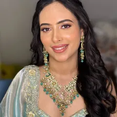 A beautiful morning Roka bride. The makeup is fresh and luminous, with a soft pink lip and defined eyes to complement her pastel blue outfit and emerald jewelry.