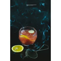 A smoky citrus cocktail against a dark, moody background. I use techniques like smoke to add drama and atmosphere, creating an alluring image for a bar's specialty drink menu.