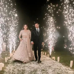 A grand entrance for Pallavi and Amit, walking hand-in-hand down a path lined with candles and bursting sparklers. A truly magical start to their celebration.