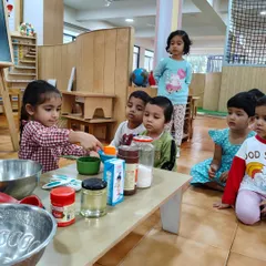 Children take turns measuring ingredients for our cake. This hands-on experience with measuring cups and spoons makes mathematical concepts like volume and fractions concrete and understandable.