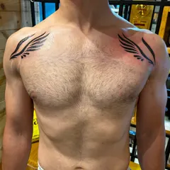 These tribal-style wings were designed to cover up some old marks on the client's chest, giving him a powerful and symmetrical new look.