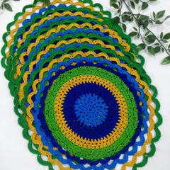 A stack of my peacock placemats, showing the beautiful layers of blue, green, and gold. They are made with high-quality cotton threads for durability.