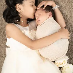 The bond between siblings is so precious. We gently guide these interactions to capture tender moments, like an older sister's protective kiss for her new baby brother.