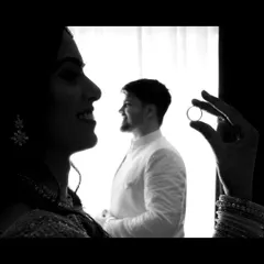 A creative and artistic black and white shot symbolizing the engagement. The bride-to-be holds the ring, framing her partner in the background, telling a powerful story of their commitment in a single frame.
