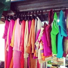 A selection of blouse pieces and fabrics hanging in my shop. I can help you find the perfect color and material for your next custom-stitched blouse.
