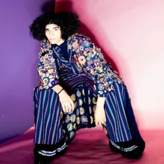 A powerful shot from a péro brand lookbook, featuring a full, natural afro style. The goal was to embrace and enhance the model's natural hair texture to complement the vibrant, layered outfit.