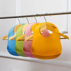 A clean, simple shot of colorful silicone baby bibs hanging on a rack. This is a perfect e-commerce photo that clearly shows the product and color variety.