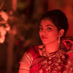 This candid reception portrait was shot with a Zeiss Otus 85mm lens, known for its incredible sharpness. The warm, moody lighting highlights the rich red of the bride's saree and the intricate details of her jewelry as she adjusts her earring.