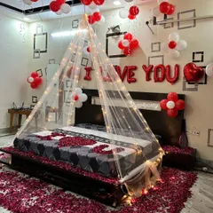 For a truly romantic gesture, we transformed this bedroom with a fairy light canopy, hundreds of red and white balloons, and a floor covered in rose petals. The "I LOVE YOU" balloon letters add a perfect finishing touch to this anniversary or birthday surprise.