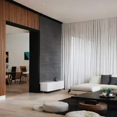 This living room design perfectly balances warmth and minimalism. The wooden fluted wall acts as a beautiful partition, while the sheer white curtains allow for soft, natural light to fill the space.