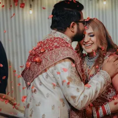 A sweet and tender moment amidst the celebration. The groom's gentle kiss on the bride's forehead, showered in flower petals, is a perfect candid shot full of love.