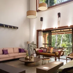 The formal living room is a study in volume and light. A twenty-foot ceiling, hand-chiseled stone flooring, and a mix of new and upcycled antique furniture create a sanctuary where the boundary between architecture and nature dissolves.