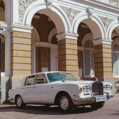 A pristine white Rolls-Royce parked in front of a grand arched building. This is the epitome of classic luxury and timeless elegance.