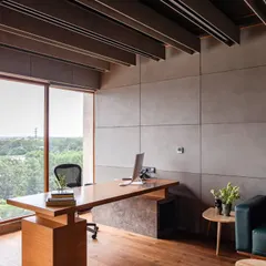A view of the main desk in the MD's office at Anthea Pharma, positioned to take advantage of natural light from a large window. The space combines a William grey marble desk surface with a deep blue lounge area, reflecting the client's preference for subtle, subdued colors.