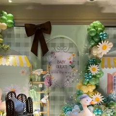 Another angle of the "Baby Gulati" backdrop, featuring a large brown bow and a beautiful balloon garland in shades of green and yellow.