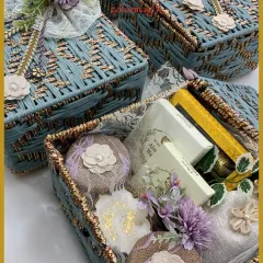 A close-up of our pastel blue woven gift baskets, filled with an assortment of treats. The delicate floral and lace embellishments add a touch of handcrafted charm.