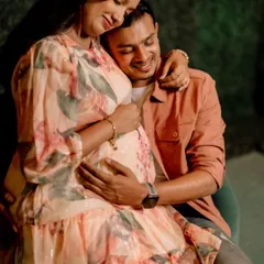 A joyful close-up of an expecting father embracing his partner from behind. His happy smile and her serene expression perfectly capture the excitement of this time.