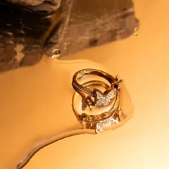 A creative jewelry shot featuring a butterfly ring in a pool of liquid gold. The reflection and texture create a magical and luxurious image.