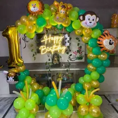 A simple yet beautiful jungle-themed balloon ring for a first birthday at home. This setup uses a neon 'Happy Birthday' sign and foil balloons of a lion, monkey, tiger, and giraffe.