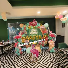 A stylish Flamingo-themed party setup in a restaurant. The tropical balloon arch, flamingo cutouts, and neon sign look fantastic against the venue's modern decor.