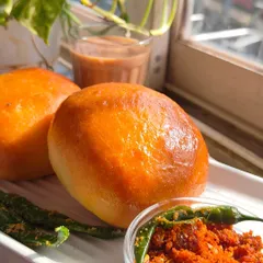 My Baked Vada Pav, served with dry garlic chutney and fried green chilies. It's a wholesome twist on a classic Mumbai street food.
