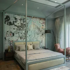 An artistic bedroom featuring a four-poster bed and a dramatic, textured accent wall that resembles aged plaster. The soft color palette of sage green and dusty rose creates a space that is both eclectic and calming.