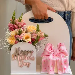 The 'Bloom Box' collaboration, a unique gift set featuring a delicate cake with an intricate pink bow alongside a fresh floral arrangement in a custom white carrier. This design showcases how I blend edible art with fresh flowers for a truly special Mother's Day gift.