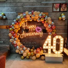 Celebrating a 40th anniversary with an elegant balloon ring in metallic tones, a custom "Happy Anniversary" neon sign, and large marquee numbers.