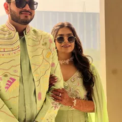 A closer look at our coordinated carnival outfits. The groom's pastel green jacket is adorned with playful, multi-colored threadwork, while her matching co-ord set features delicate embellishments and a flowing cape for a fun, festive vibe.
