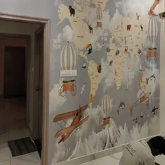 An educational and adventurous world map mural being installed in a child's room, featuring animals native to different continents.
