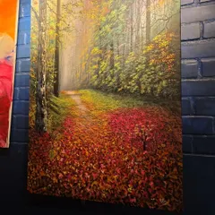 The beauty of autumn is captured in this stunning landscape painting. The path covered in fallen red leaves invites you to take a stroll through the forest, bringing the warmth and color of the season indoors.