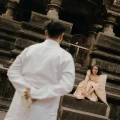 A playful glance on ancient temple steps. He approaches with a hidden 'gajra', a classic romantic gesture that we brought to life in this traditional pre-wedding shoot.