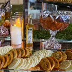 A selection of dips and crackers from our grazing table. We use elegant crystal bowls and silver trays to present items like pesto, tomato chutney, and assorted crisps, ensuring every detail is perfect.