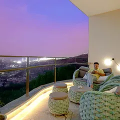 A stunning twilight view from a high-rise balcony we designed. The comfortable, woven outdoor furniture and ambient lighting create the perfect spot to relax and enjoy the city skyline.