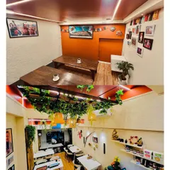 Our dining space is designed to be cozy and intimate. The top image shows our traditional low-seating area for a more authentic experience, while the bottom image gives a view of the main dining floor, decorated with greenery and warm lighting.