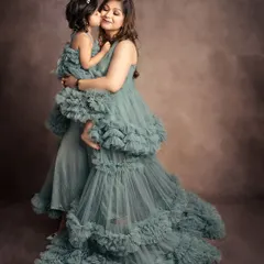 A magical mother-daughter moment. Wearing matching ruffled gowns from my studio wardrobe, they share a sweet kiss, looking like royalty.
