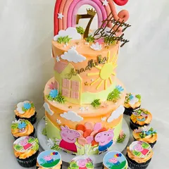 A cheerful two-tier Peppa Pig cake, perfect for a sunny 7th birthday. This design features a warm sunset color palette, a rainbow topper, and adorable edible prints of Peppa and George, complete with matching themed cupcakes.