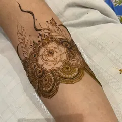 Another angle of Nida's armband, showing the fine lines and delicate leaves surrounding the central rose.