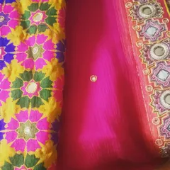 This image shows a combination of fabrics for a festive outfit. On the left is a colorful phulkari-style embroidered fabric with mirror work, paired with a sheer pink georgette that has a detailed embroidered border.