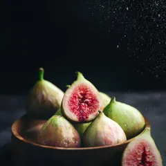 A dark and moody still-life of fresh figs, with a spritz of water captured mid-air to enhance their freshness and add drama.