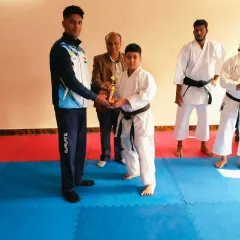 A young student receiving his black belt award. It's a proud moment for him and a great achievement at his age.